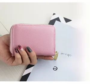 Detailed view of a pink litchi grain leather wallet with a secure gold metal zipper
