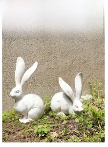 Detalle de dos estatuas de conejos vintage en hierba con acabado en marfil envejecido
