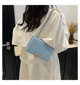 Detail of light blue crossbody bag with diamond quilted texture and gold chain strap