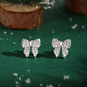 Macro shot of silver bow stud earrings with shimmering cubic zirconia on dark background
