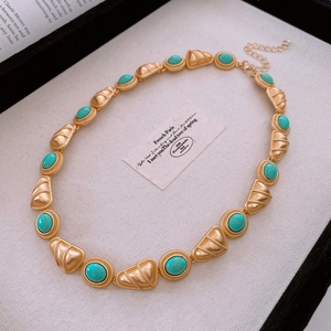 Detail view of a vintage gold necklace with turquoise stones and textured metal reliefs