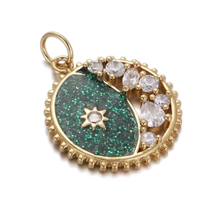 Macro detail of crescent moon and star gold pendant with green glitter and cubic zirconia
