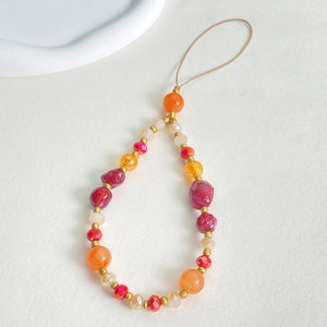 Macro detail of handmade colorful resin beads and gold accents on a beaded phone strap