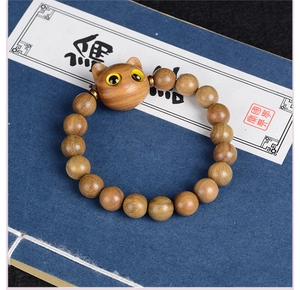 Gros plan d'un bracelet en bois de santal avec perle chat sur un livre ancien