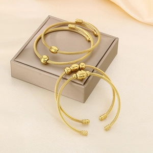 Elegant gold twisted cable wire cuff bracelets displayed on a luxury jewelry gift box