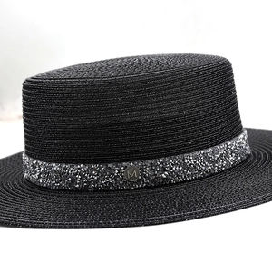 Détail du chapeau de paille noir avec bande de strass argentés et logo métallique lettre M