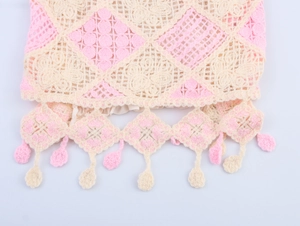 Detail of pink and beige crochet knit camisole featuring hollow diamond patterns and tassels