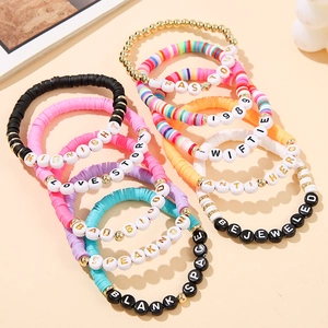 Close-up of stacked colorful clay bead bracelets with Taylor Swift era letter charms