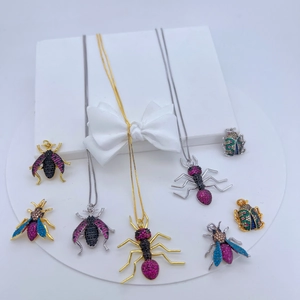 Detailed view of copper insect pendants with colorful cubic zirconia on white pedestals