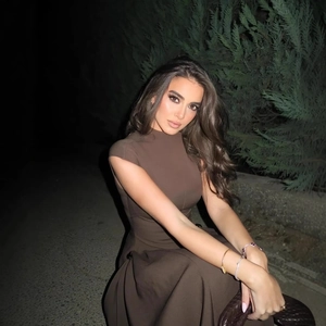 Elegant sleeveless brown pleated dress with metal buckles and a woven handbag