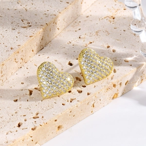 Macro shot of 18k gold plated heart earrings with pavé set crystals on a stone