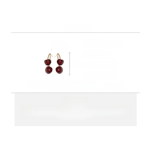 Detailed view of red resin cherry earrings with copper stems and silver needle posts