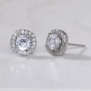 Macro shot of silver-plated flower stud earrings with clear zircon on marble surface