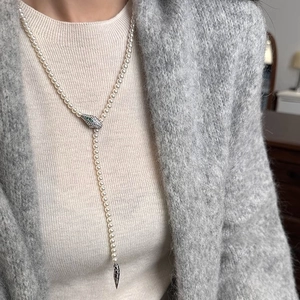 Elegant Y-shaped pearl necklace with a green-eyed snake head clasp and metal tassel