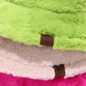 Detail of plush bucket hat with brown faux leather snowflake label in various colors