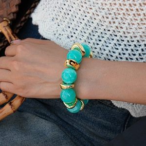 Detail of blue resin beads and wavy gold spacers worn by a model in casual chic attire