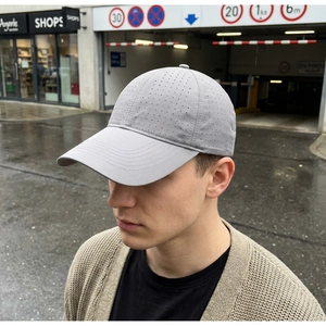 Close-up of light grey baseball cap with laser-cut holes and decorative brim stitching