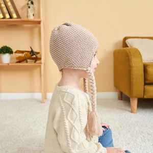 Beige chunky knit baby winter hat with braids, tassels, and fleece lining for warmth
