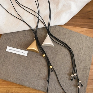 Detail of matte gold and silver triangle pendants on black adjustable leather cords