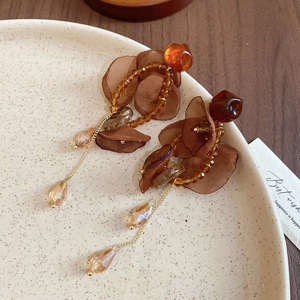 Close-up of amber tulle flower earrings with crystal teardrops and golden chain details