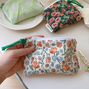 Gros plan sur une mini pochette plissée en coton avec imprimé floral et fermeture