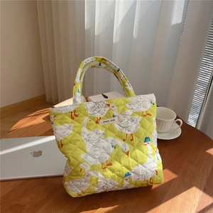 Detail of a yellow quilted tote bag featuring white goose prints and simple wish label
