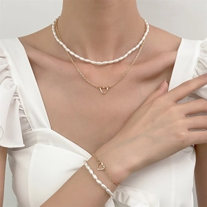 Close-up of a double-layered pearl and gold heart necklace on an elegant woman