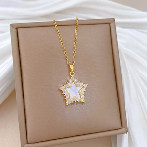 Luxurious gold star necklace with shell center and cubic zirconia on silk background