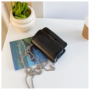 Detailed macro view of black crocodile pattern faux leather bag with silver chain