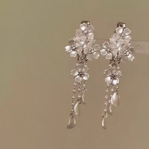 Close-up detail of ethereal white flower hair clips with elegant pearl tassels and petals