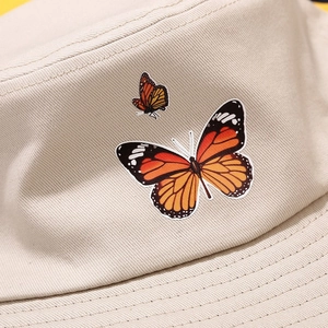 Gros plan de la broderie papillon sur le bob en sergé de coton beige de haute qualité