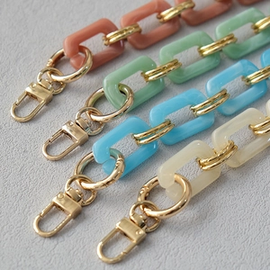 Macro view of pastel acrylic bag straps with golden metal lobster clasps in four colors