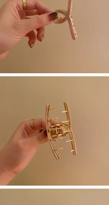 Detailed close-up of matte pink hair claw clip with golden metal spring and teeth