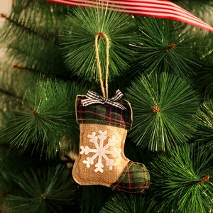 Gros plan d'une chaussette de Noël en toile de jute avec flocon de neige sur un sapin