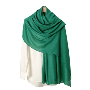 Solid green linen feel scarf for women draped over a white shirt for autumn winter style