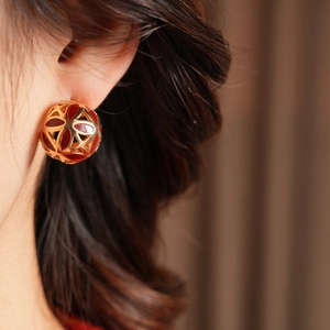 Gros plan de boucles d'oreilles boules dorées vintage avec émail rouge sur le lobe