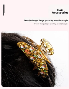 Detail of Christmas claw clip with gold stars and Santa motif on dark long hair