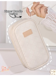 Detailed close-up of woven cream pencil case with zipper handle and premium leather tag
