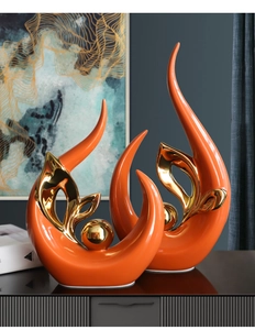 Close-up of modern orange ceramic sculptures with gold electroplated hollow accents