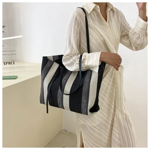 Detail view of large striped woven tote bag showing vertical texture and leather straps