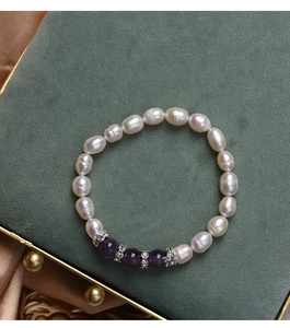 Detail of freshwater pearl and purple agate bracelet on a green velvet jewelry box