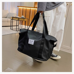 Detail of a black large-capacity travel bag with durable straps and white woven logo