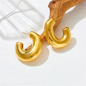 Detailed view of hollow gold-plated teardrop earrings with crystals on a branch