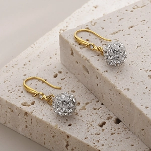 Détails macro de boucles d'oreilles dorées avec sphères serties de cristaux scintillants