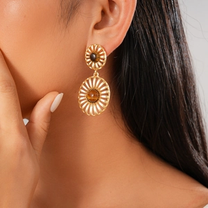 Detail of vintage gold hollowed-out earrings with tiger eye stone on a female model