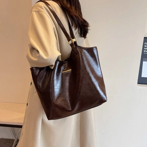 Large coffee brown oil-wax leather tote bag with gold buckle shown on model