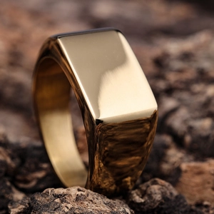 Minimalist gold square signet ring in polished stainless steel on wood background