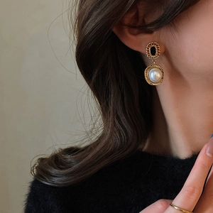Gros plan de boucles d'oreilles vintage en or avec pierres noires et perles sur mannequin