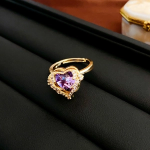 Macro shot of an adjustable gold ring with a heart-shaped purple zircon and diamond halo