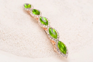 Detail of marquise green crystals and white rhinestones on a rose gold hair clip base
